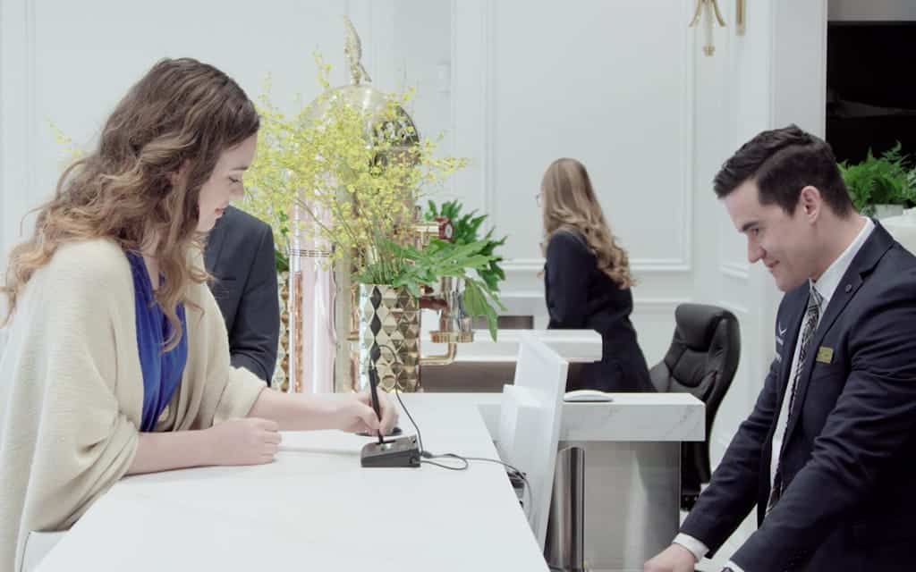 A man and woman stand at a hotel reception desk-Condor Concierge